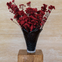 RUBY deep red preserved rice flower in Lashay tall vessel amber on a timber plinth